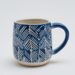 handmade ceramic mug with cuerda seca decoration, navy blue and white geometric pattern, dark wax resist outlines, matte glaze, studio pottery, clean white background, product photography