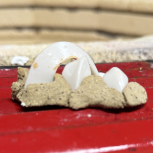 Close up of broken white eggshell fragments and crumbs on a red tray or surface